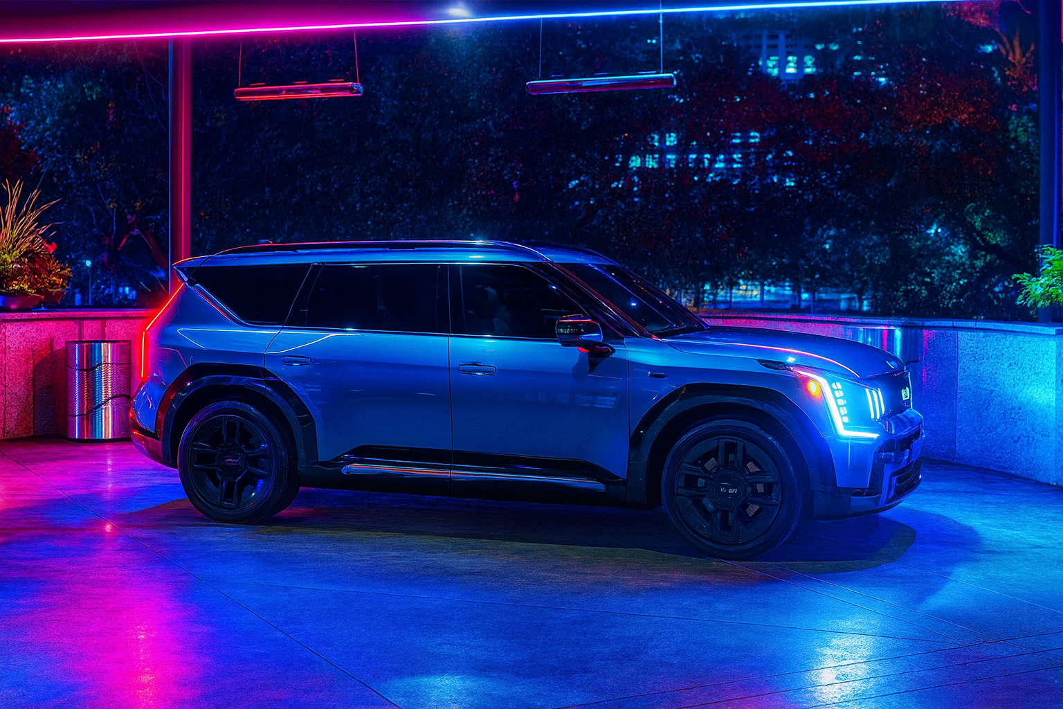 Ocean Blue Kia EV9 illuminated in a dramatic blue and magenta setting